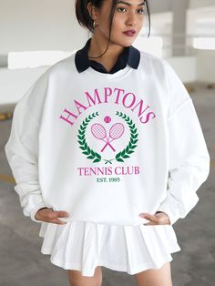 a woman wearing a white sweatshirt with pink tennis rackets on it