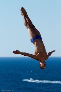 a man diving into the water from a boat in the ocean while wearing a blue swimsuit