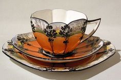 an orange and black flowered tea cup sitting on top of a saucer set