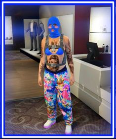 a person with a dog on their chest wearing a blue mask and colorful sweatpants