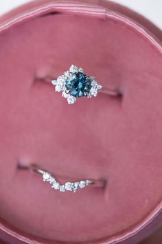 two engagement rings sitting on top of a pink velvet box