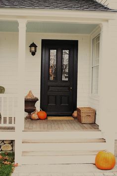 a black front door with two pumpkins on the steps