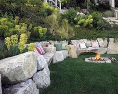 an outdoor fire pit surrounded by rocks and grass