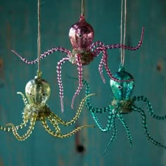 three octopus ornaments hanging from strings on a blue wall