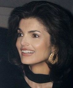 a woman sitting in the back seat of a car wearing large gold earring earrings