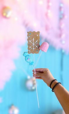 a person is holding up some kind of paper snowflake and heart shaped lollipops