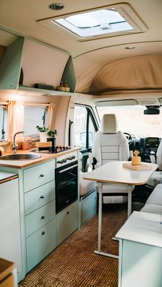 the interior of a camper with an oven, sink, and table in it