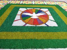 a colorful carpet with a bird painted on the grass and flowers in the center,