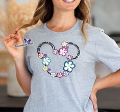 ☆☆☆ We offer large Group order discounts. Send us a message! Elevate your wardrobe with a touch of Disney magic! Our soft shirt featuring the iconic Minnie Mouse silhouette adorned with vibrant colorful flowers and glitter details is the perfect blend of cute and chic. Add a dash of sparkle to your day and let Minnie's timeless charm brighten every moment. Available now for a touch of Disney whimsy in your style! Whether it's a family gathering, a Disney-themed outing, or just a cozy day at home, these personalized t-shirts are the perfect choice. They combine the magic of Disney with the warmth of family connections, ensuring that every time you slip one on, you're reminded of the love that binds your family together. Share the joy, laughter, and memories with our personalized Disney soft Minnie Mouse Silhouette, Silhouette Head, Mouse Silhouette, Disney Tee, Disney Tees, Flower Shirt, Hibiscus Flowers, Crew Neck Shirt, Disney Style