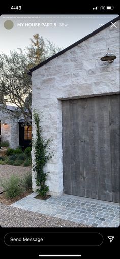 an old white brick building with a wooden garage door and ivy growing on the side