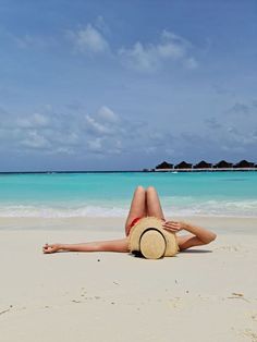 a woman laying on top of a sandy beach