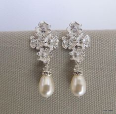 "These elegant earrings have small flower pendants in matte rhodium plated finish and Swarovski teardrop pearls. Ivory/cream Swarovski pearls measure 11 mm long. Earrings are approximately 1 1/2\" long from top to bottom by 1/2\" wide. Each flower has a tiny clear cubic zirconia in the center. Post is .925 sterling silver over brass. Please choose desired pearl color and finish at checkout. Perfect for any nature inspired bride! Matching necklace, https://www.etsy.com/listing/274801382/backdrop- Teardrop Pearl Drop Chandelier Earrings, Teardrop Pearl Drop Clip-on Earrings For Wedding, Pearl Teardrop Earrings For Mother Of The Bride, Teardrop Pearl Earrings For Anniversary, Teardrop Chandelier Earrings With Pearl Drop, Teardrop Pearl Bridal Earrings For Mother Of The Bride, Wedding Teardrop Earrings With Pearl Drop, Delicate Flower Pearl Drop Earrings, Formal Pearl Drop Dangle Flower Earrings