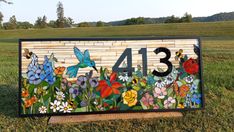 a house number sign with flowers and butterflies painted on it