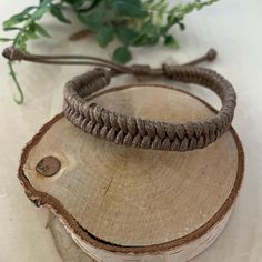 a close up of a piece of wood with a rope on it and flowers in the background