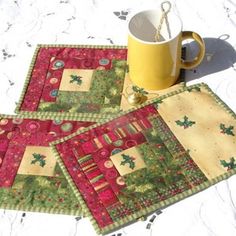 three quilted placemats on a table with a coffee cup in the middle