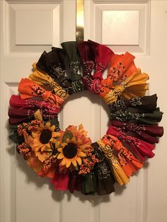 a wreath made out of scarves and sunflowers hangs on the front door