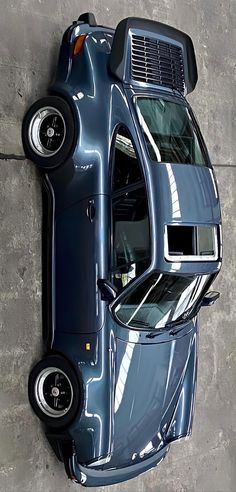 an overhead view of a blue truck parked on the side of a building with its hood up