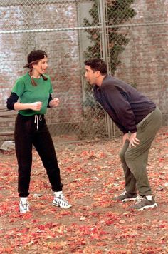 a man and woman standing next to each other in front of a chain link fence