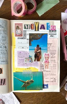 an open book on a wooden table with various papers and washi tape around it