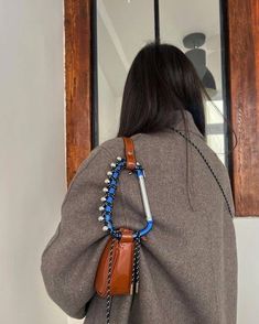 the back of a woman's jacket with beads and chains hanging from it, in front of a window