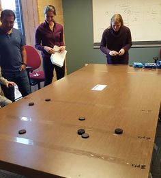 four people standing around a table with coins on it