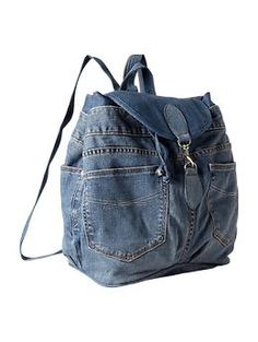 a denim backpack with zippers on the front and side pockets, attached to a shoulder strap