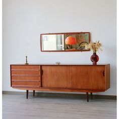 a wooden cabinet with two vases on top of it and a mirror above it