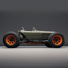 an old model car with orange rims on the front and side wheels, sitting against a gray background