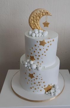 a three tiered white cake with gold stars and a crescent on top, sitting on a table