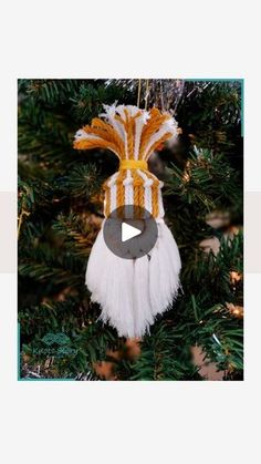 an ornament hanging from a christmas tree decorated with white and yellow yarns