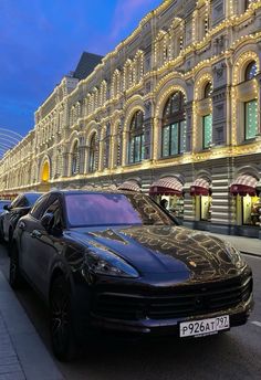 a black car parked on the side of a street next to a building at night