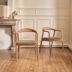 two chairs sitting next to each other in front of a fire place on a hard wood floor