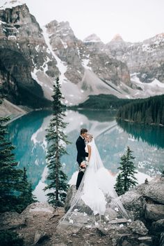 a bride and groom standing on top of a mountain