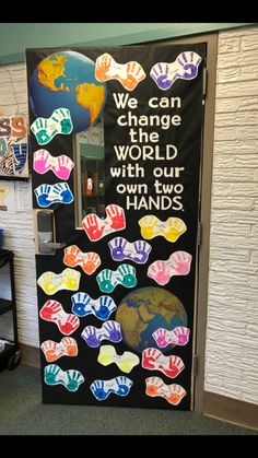 a classroom door decorated with handprints and the words we can change one world with our own two hands