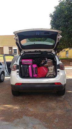 the back end of a car with its trunk open and suitcases packed in it