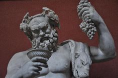 a statue of a man holding grapes in his hand