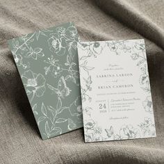 two wedding cards sitting on top of a bed next to each other, one is green and the other is white