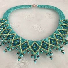 a blue and green beaded necklace on a white surface