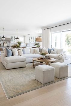 a living room filled with white furniture and lots of pillows on top of a rug