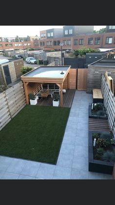 a small backyard with a hot tub and green grass on the ground, surrounded by buildings