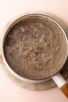 a cup of coffee on top of a saucer next to a wooden spatula