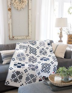 a living room filled with furniture and a large quilt on the couch next to a window