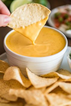 a tortilla chip being dipped into a bowl of salsa