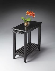 a small black table with a flower on top and shelf underneath the table for storage