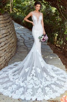 a woman in a wedding dress standing on a stone path with her hands on her hips