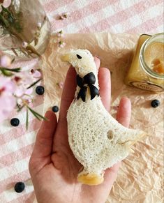 a person holding a piece of bread with a stuffed duck on it's side