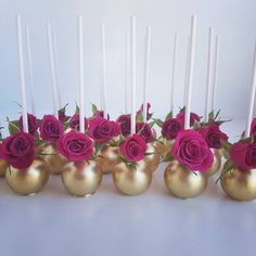 there are many gold vases with pink roses in them and candles on the side