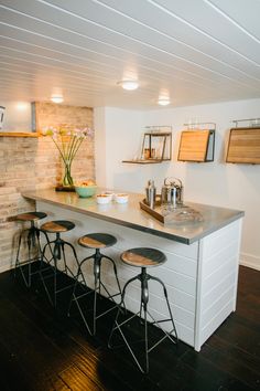 an image of a kitchen setting with bar stools and counter top area in the center