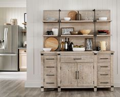 a kitchen with wooden cabinets and stainless steel refrigerator in the back ground, along with white walls