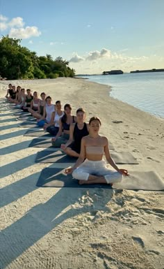 a group of people doing yoga on the beach